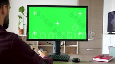 人坐在电脑前的侧视图，键盘上输入绿色大屏幕模拟色度