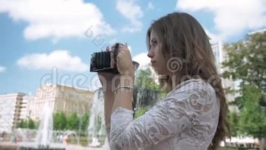 美丽的女孩用老式相机拍摄城市<strong>景点</strong>的照片