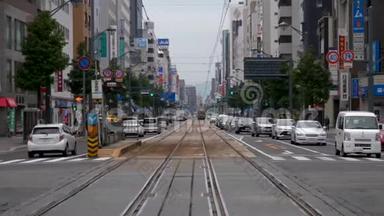 一辆电车沿着日本广岛市的一条街道汽车线驶近。