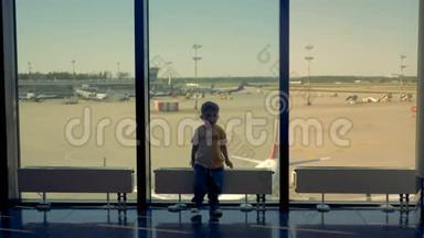 一个男孩在机场休息室玩。 一个孩子看着相机，在机场的窗户附近玩耍。