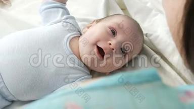 一个两个月大的快乐<strong>新生儿躺</strong>在床上，向母亲体验情绪。 孩子笑，说，浪