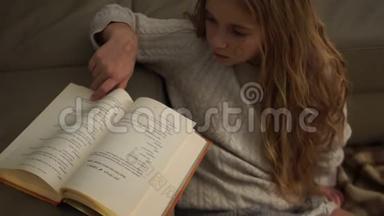 <strong>少女</strong>坐在满是格子地毯的地板上<strong>看书</strong>。 圣诞节，灯光，家庭舒适