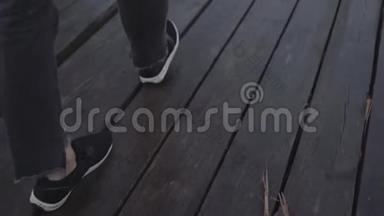 穿着运动<strong>鞋</strong>和黑裤子的女人走在<strong>潮</strong>湿的木板码头上