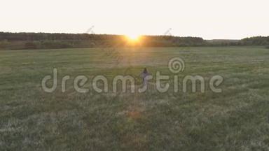 无法辨认的女人在日落时走在田野上，手臂伸出。