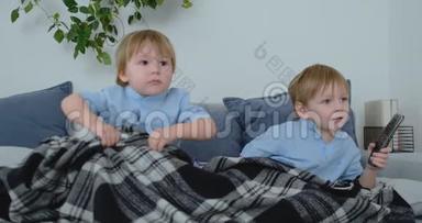 两个孩子在电视上看一个令人兴奋的电视节目。 两个兄弟在看电视