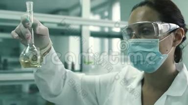 漂亮的实验室技术人员用化学液体把烧瓶剥开