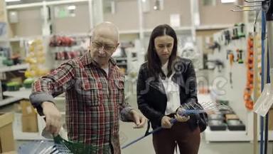 一位老人和成年女儿在五金超市选择耙子