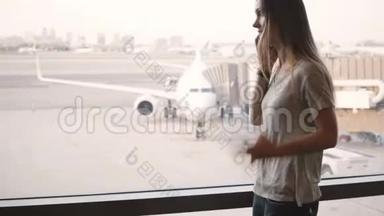 年轻的欧洲妇女在机场候机楼窗口附近打电话，错过航班后心烦意乱。
