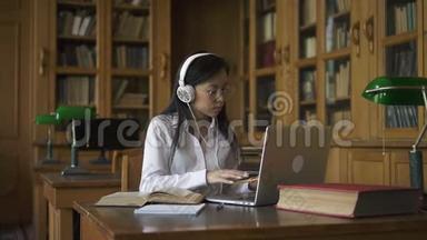 年轻漂亮的女人在研究<strong>话题</strong>，坐在桌子上，手提电脑在图书馆。