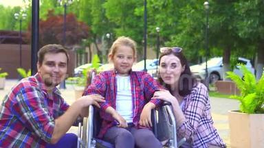看镜头的画像爸爸妈妈带着一个残疾的小女儿坐在轮椅上，开心
