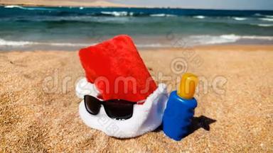 圣诞老人帽子躺在沙滩上的4K镜头。 在热带岛屿庆祝圣诞节的概念