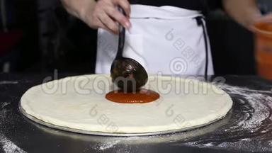 厨师在厨房的披萨上放番茄酱。