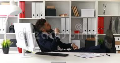 年轻的商人在办公室工作，腿在桌子上。