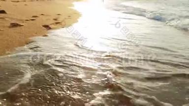 日落时分，沙滩上潮湿的沙滩上的脚印上翻滚着海浪4k视频