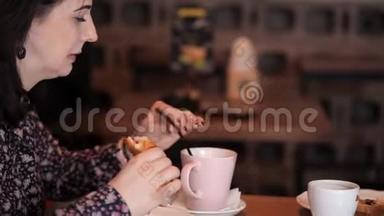可爱的夫妇在咖啡馆里聊天，吃羊角面包和三明治，喝咖啡饮料