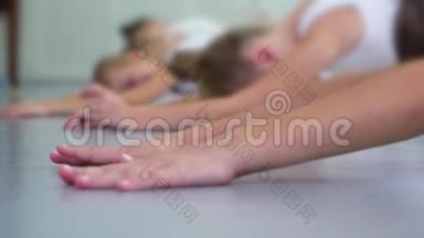 在芭蕾舞学校的慢动作练习中，特写小芭蕾舞演员在地板上伸展