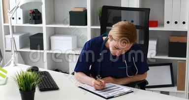 医生填写表格，弯曲在桌子上。
