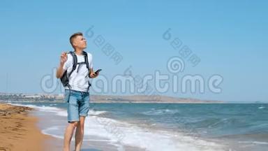 一个年轻人走在沙滩上，用手机拍了一只海鸥。