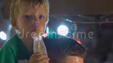 在泰国的一个夜市上，小男孩坐在父亲的脖子上`着新鲜的果汁。 泰国菜的概念。 亚洲