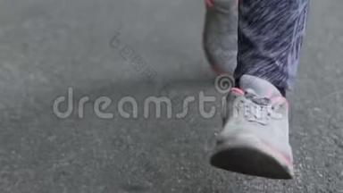 穿着跑鞋的女人在城市里用混凝土跑步，慢跑的女人的脚慢