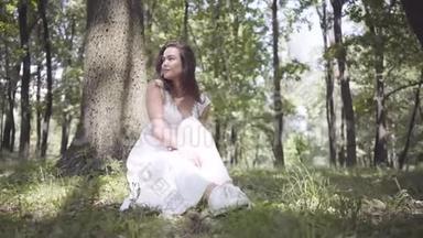 画中一个可爱的年轻女孩，留着长长的黑发，身穿白色夏季时装长裙，<strong>坐在</strong>一棵<strong>树下</strong>
