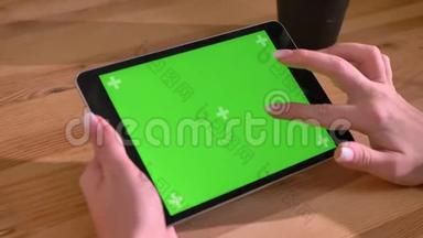 水平平板电脑的特写镜头和在木桌背景上的绿色<strong>屏幕</strong>上的手<strong>滚动</strong>。