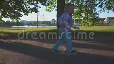 快乐<strong>的</strong>小男孩在公园和<strong>湖边的人</strong>行道上奔跑，微笑着慢动作