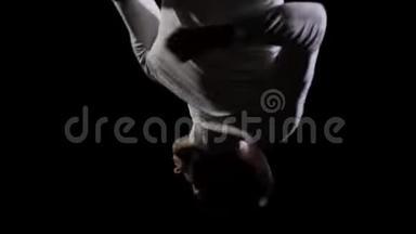 穿着白色衣服、黑色背景的英俊男体操<strong>运动</strong>员，在<strong>蹦床</strong>上缓慢地跳跃，表演翻转和跳跃