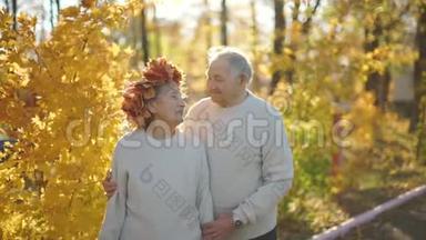 在一个美丽的秋天环境中，一对<strong>老</strong>年夫妇在公园里拥抱和微笑。 <strong>老了</strong>