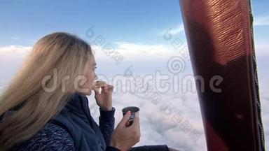 女人在飞行中吃三明治，喝茶和咖啡。 在热气球上冒险。 飞翔在清晨的蓝天之上