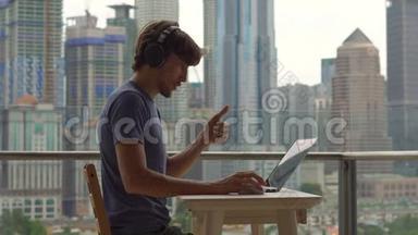 年轻的自由<strong>职业</strong>者在阳台上的笔记本电脑上工作，背景是一个充满摩天大楼的市中心。 自由<strong>职业</strong>者