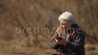 慢动作的幸福老妇人笑<strong>着看着</strong>智能<strong>手机</strong>的屏幕。 幸福的老年妇女肖像