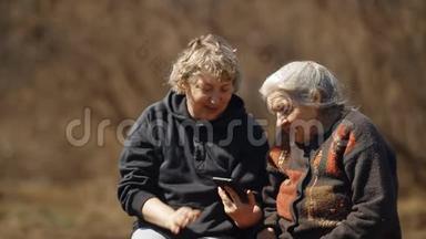 一个女人教她的老母亲使用智能手机。 两个女人看智能<strong>手机图片</strong>的肖像。