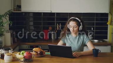 积极快乐的白种人，漂亮的卷发少女，坐在桌旁和笔记本电脑上听音乐的人聊天