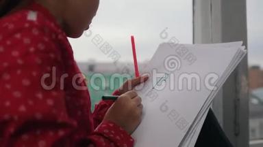 一个女孩坐在窗台上用彩色<strong>铅笔画画</strong>