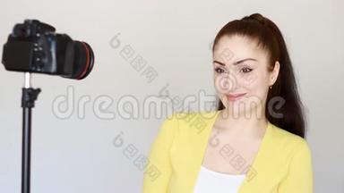 年轻的美女正在摄影棚的镜头前进行一次白色背景的采访