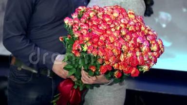 和丈夫在一起的女孩捧着一大束粉色玫瑰。 未来新娘盛宴的概念..