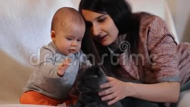 一个年轻的女人教她的小儿子对待宠物。 妈妈和宠物猫宝宝.. 慢镜头。