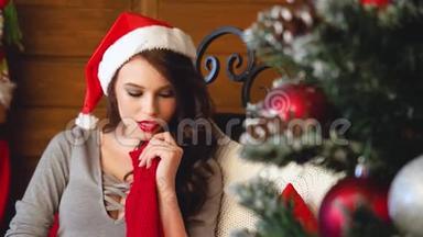 <strong>圣诞老人</strong>戴着<strong>圣诞老人帽子</strong>的年轻女子在装饰圣诞树附近的肖像。 很漂亮的女人微笑。 新年