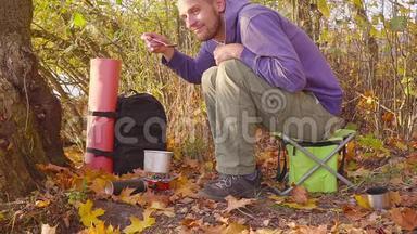 在秋天的森林里烧煤气。 游客试着从锅里取出食物。