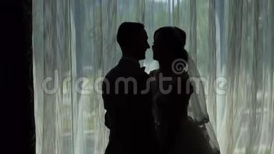新娘和新郎靠近一扇明亮的窗户。 结婚纪念日。 剪影。