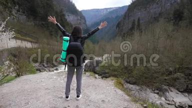 徒步旅行者女士背着背包在山上和山河湖上寻找，女孩在旅途中欣赏大自然的全景