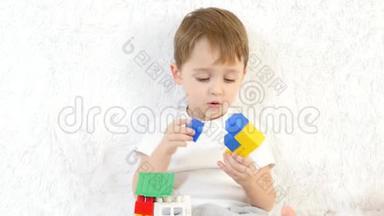 <strong>小</strong>男孩<strong>搭建</strong>了一个彩色积木玩具屋，坐在白色背景上，特写镜头.. 孩子和玩具。
