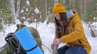 女孩<strong>游客</strong>在冬天白雪覆盖的<strong>森林</strong>里喝着热水瓶里的茶。