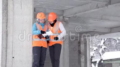 建筑工人和<strong>工程师</strong>在施工<strong>现场</strong>交谈。 在大楼外戴头盔的工人