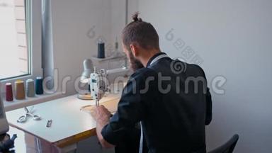 裁缝在自己的工作室里开始缝制时尚男士`衣服