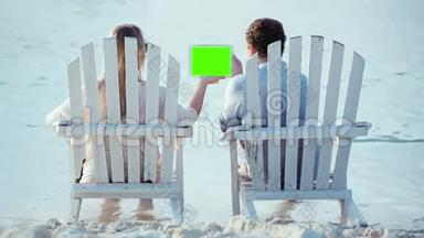 女人和男人坐在沙滩上看着