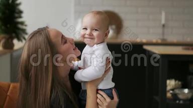 妈妈抱着宝宝，孩子微笑着看着心爱的妈妈.. 圣诞节时一起站在白色的厨房里