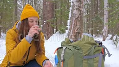女孩<strong>游客</strong>在冬天白雪覆盖的<strong>森林</strong>里喝着热水瓶里的茶。