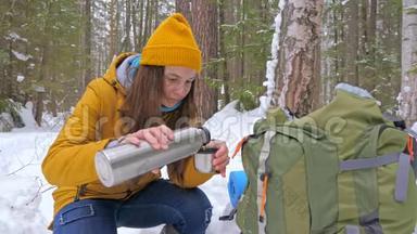 女孩游客在冬天白雪覆盖的森林里<strong>喝</strong>着<strong>热水</strong>瓶里的茶。